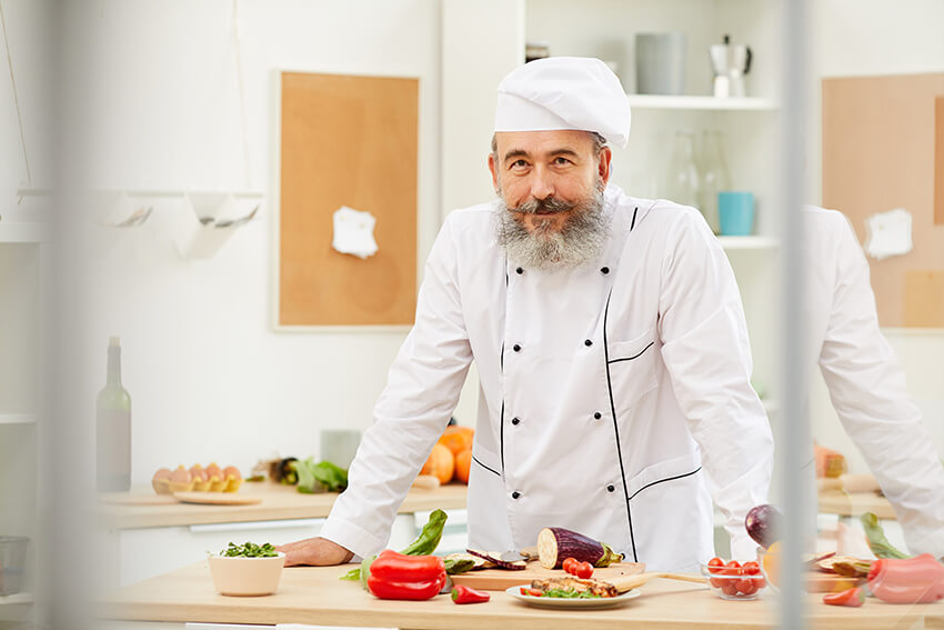 senior-chef-posing-in-kitchen-A7X9AMF.jpg